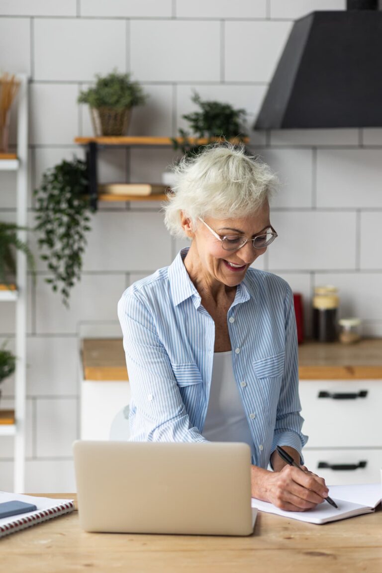 Novellus Clairemont | Senior woman looking at laptop on kitchen counter