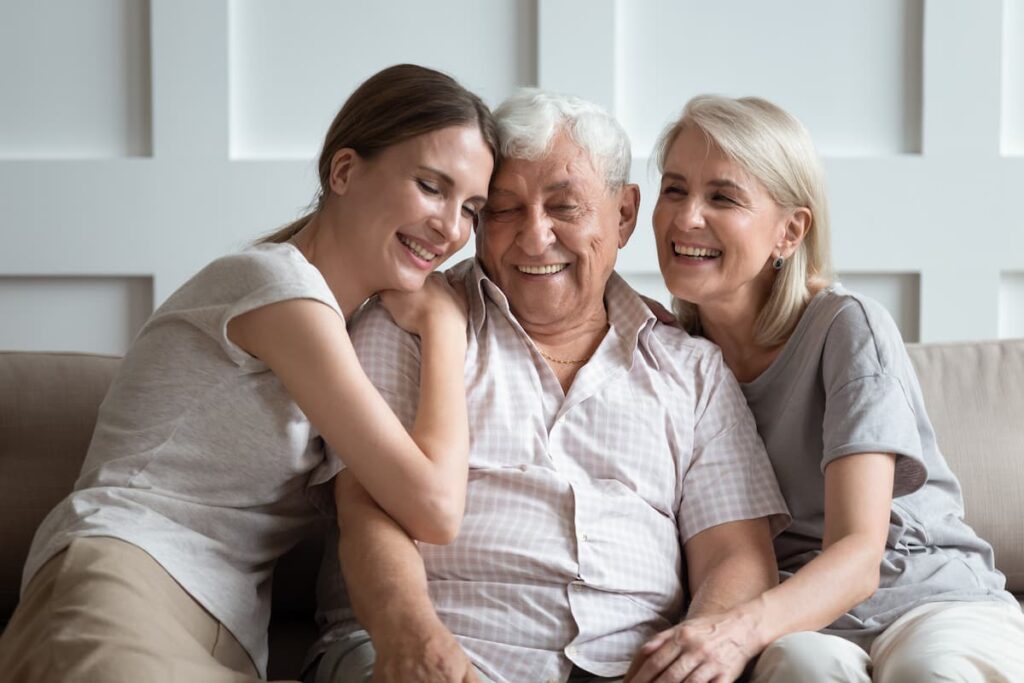 Barton House Memory Care | Senior and Family Sitting On Couch